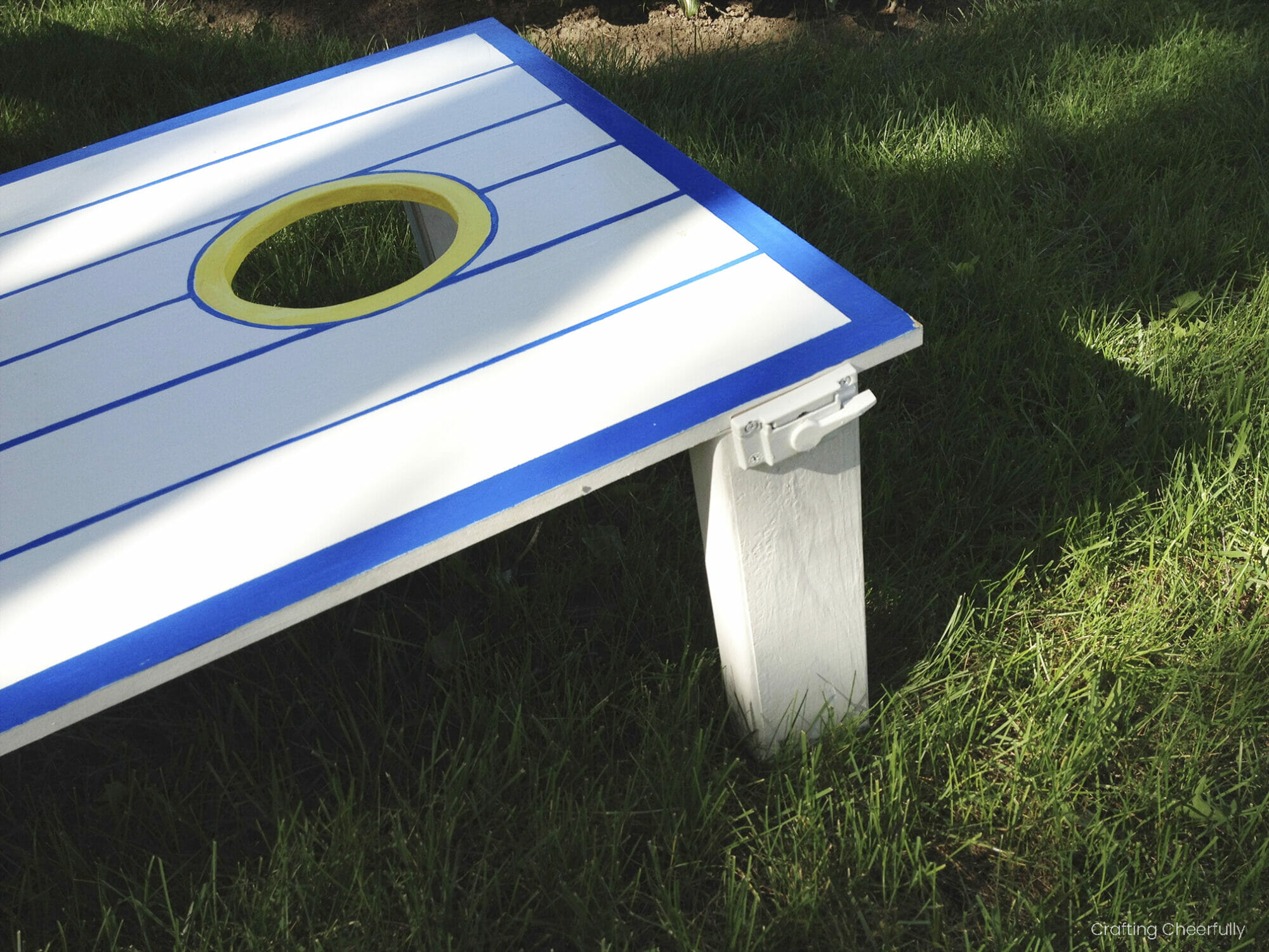 The board is set up in the grass with the hinged legs down.