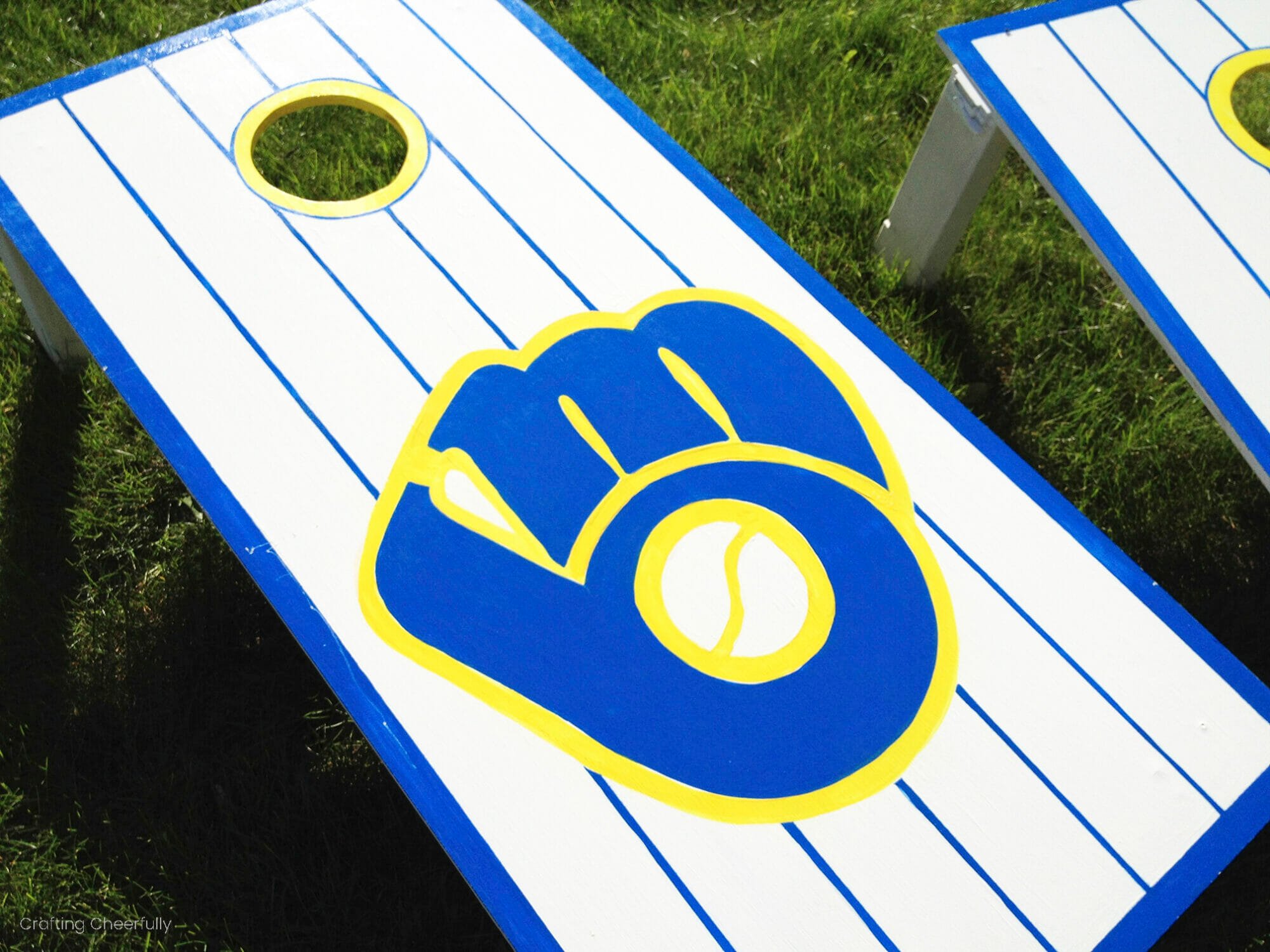 A cornhole board with a stenciled baseball logo.
