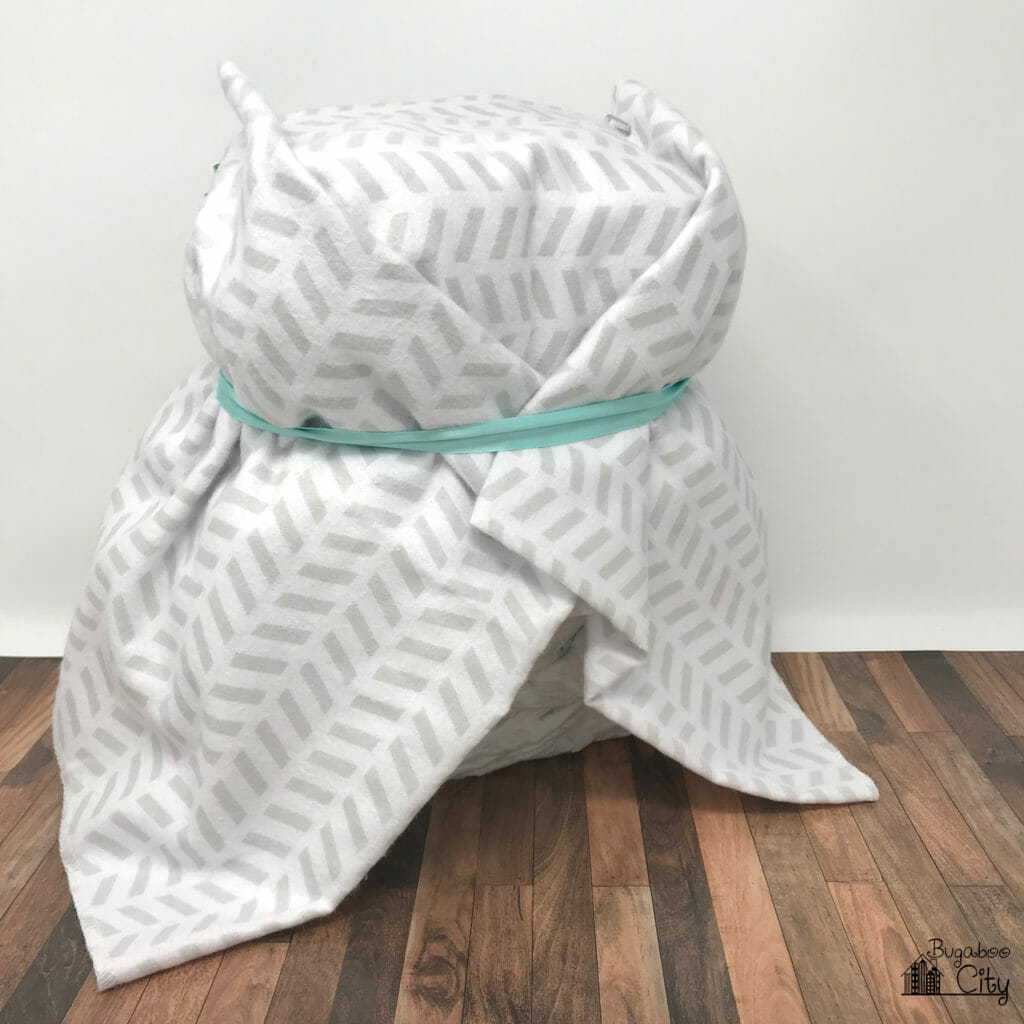 The back of the owl diaper cake showing the blanket crossed over itself, held in place by a teal ribbon.