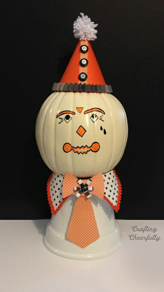 Vintage clown pumpkin sitting on an upside down pot.