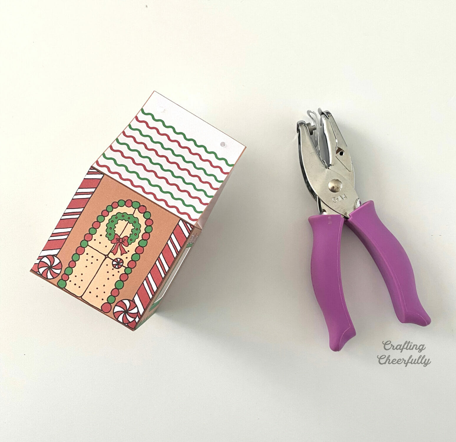 A gingerbread treat box sits next to a hole punch.
