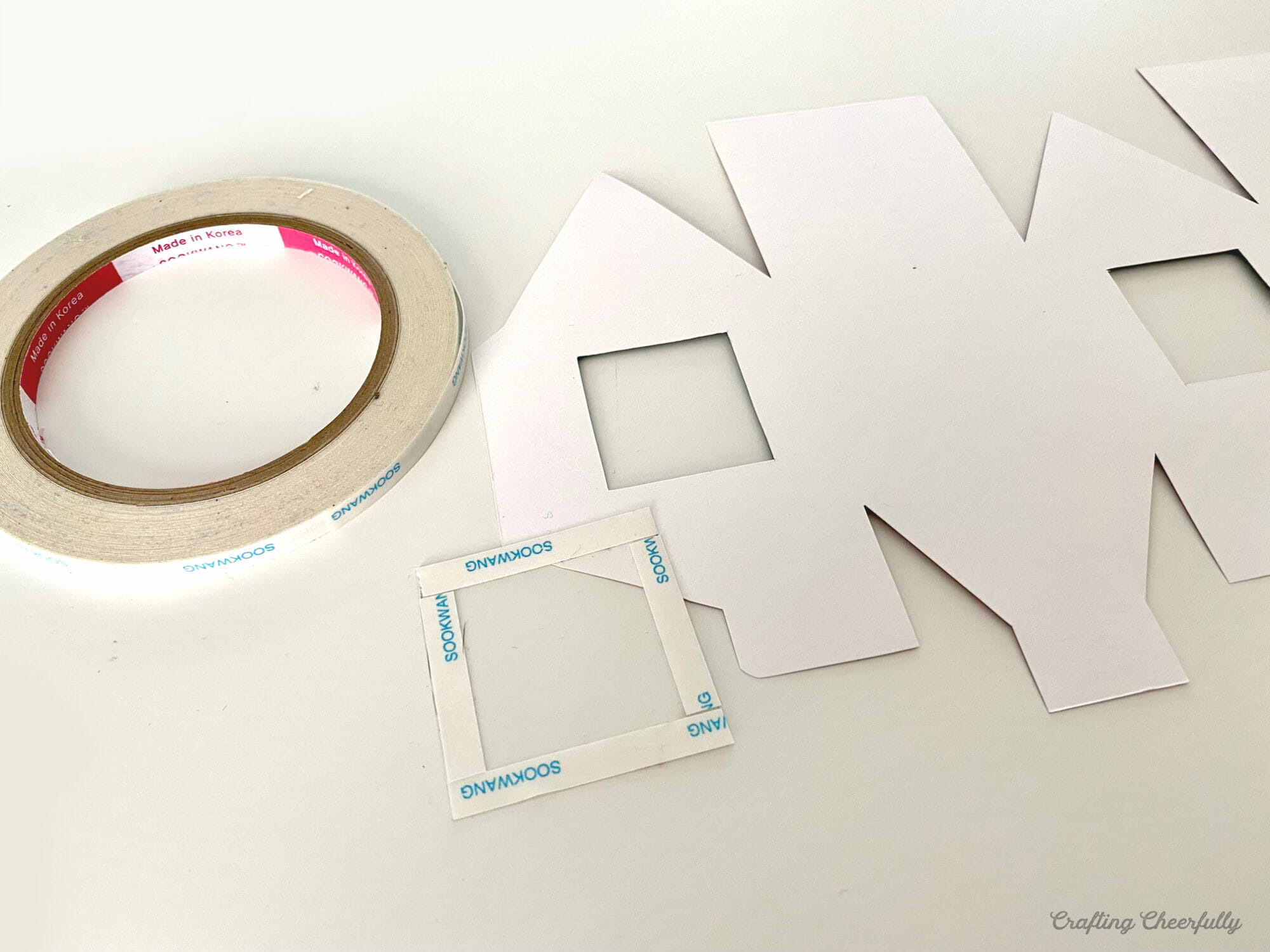 A printable gingerbread box lays on a table with clear craft plastic.