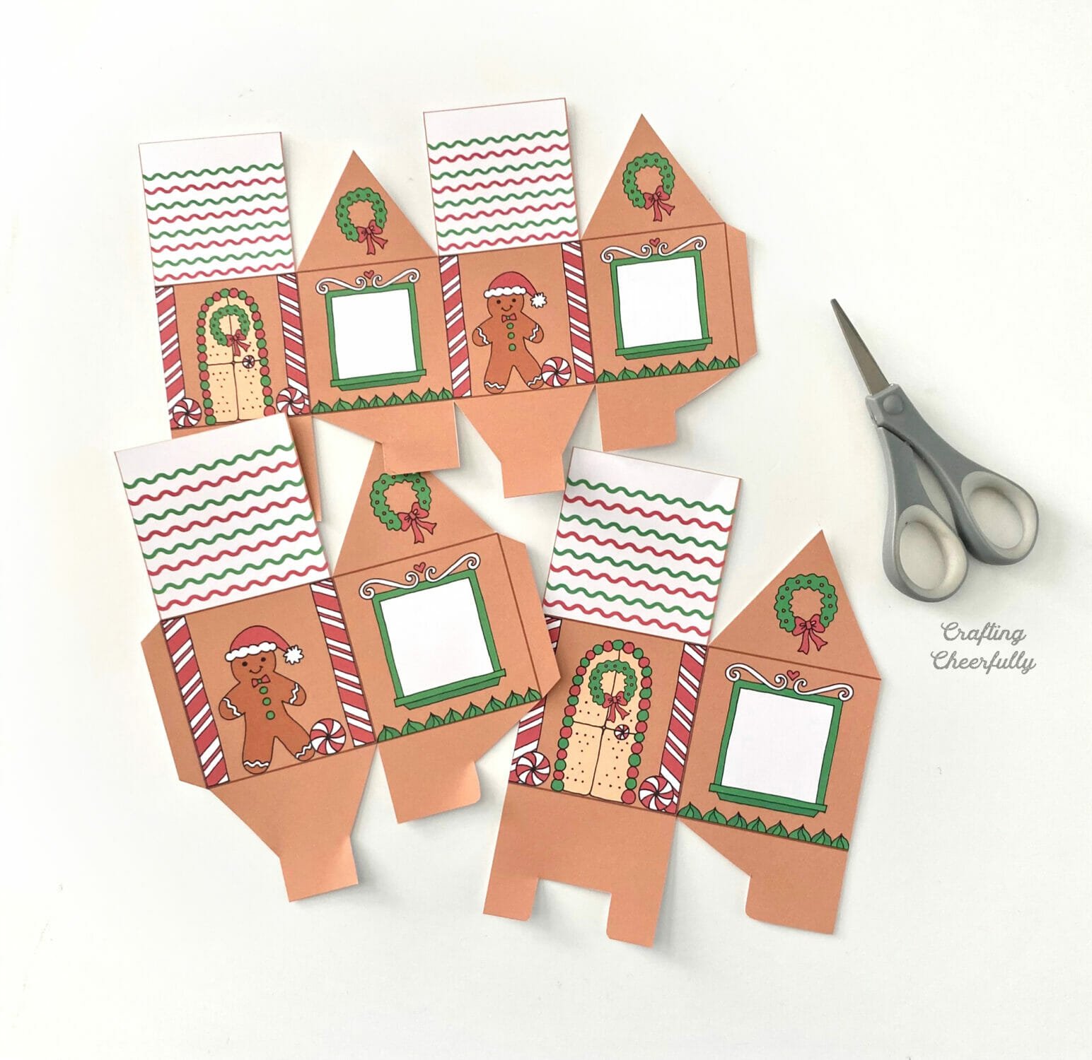 Two gingerbread house treat boxes lay next to a scissors.
