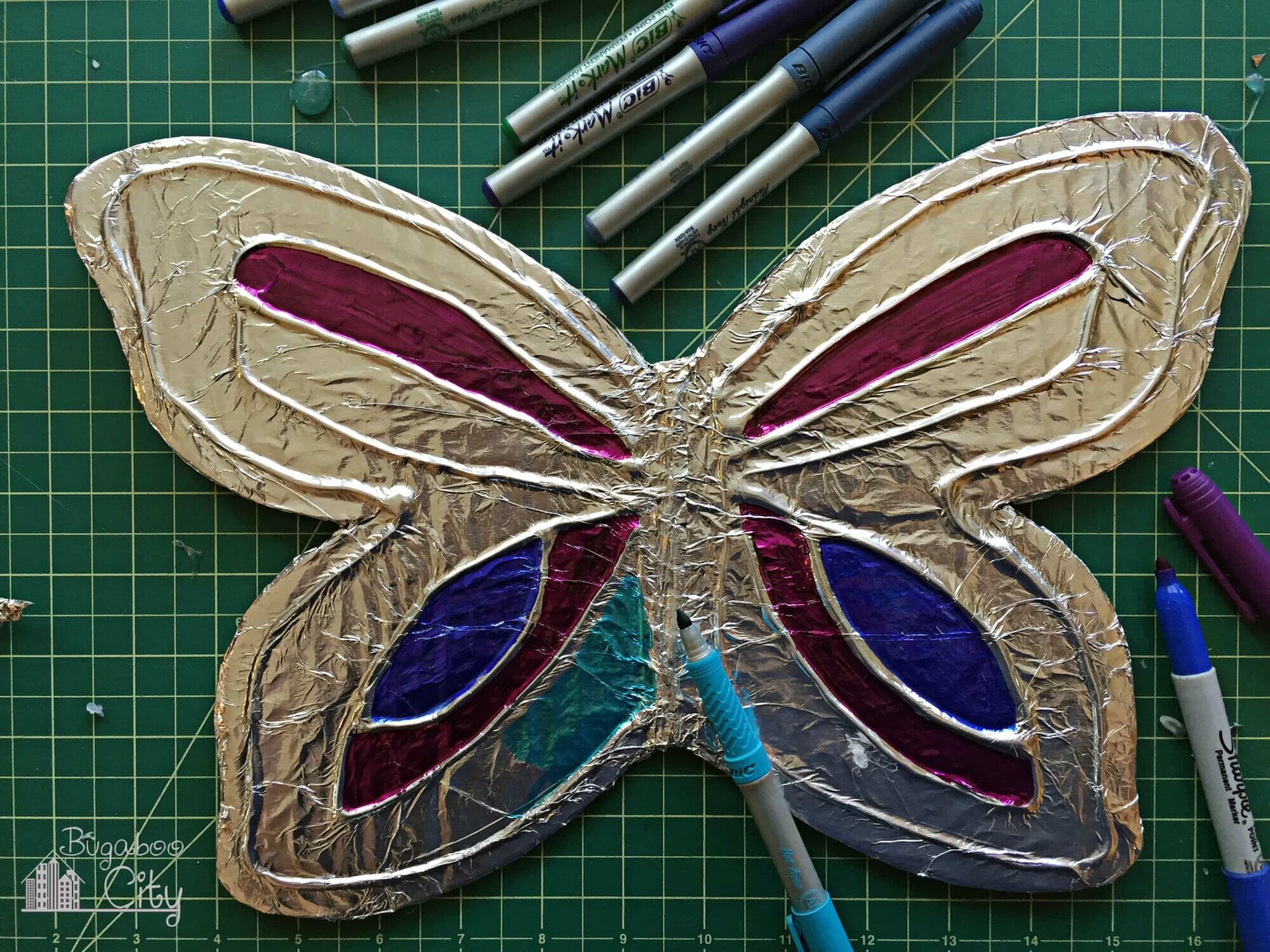 Markers color in the areas of tin foil between the hot glue designs.