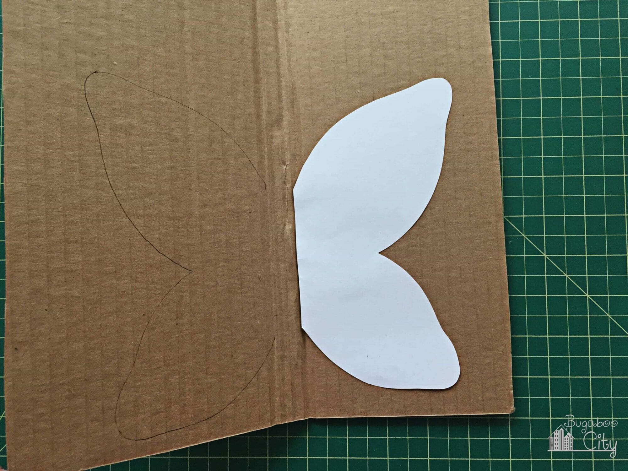 A paper wing template is traced onto cardboard.