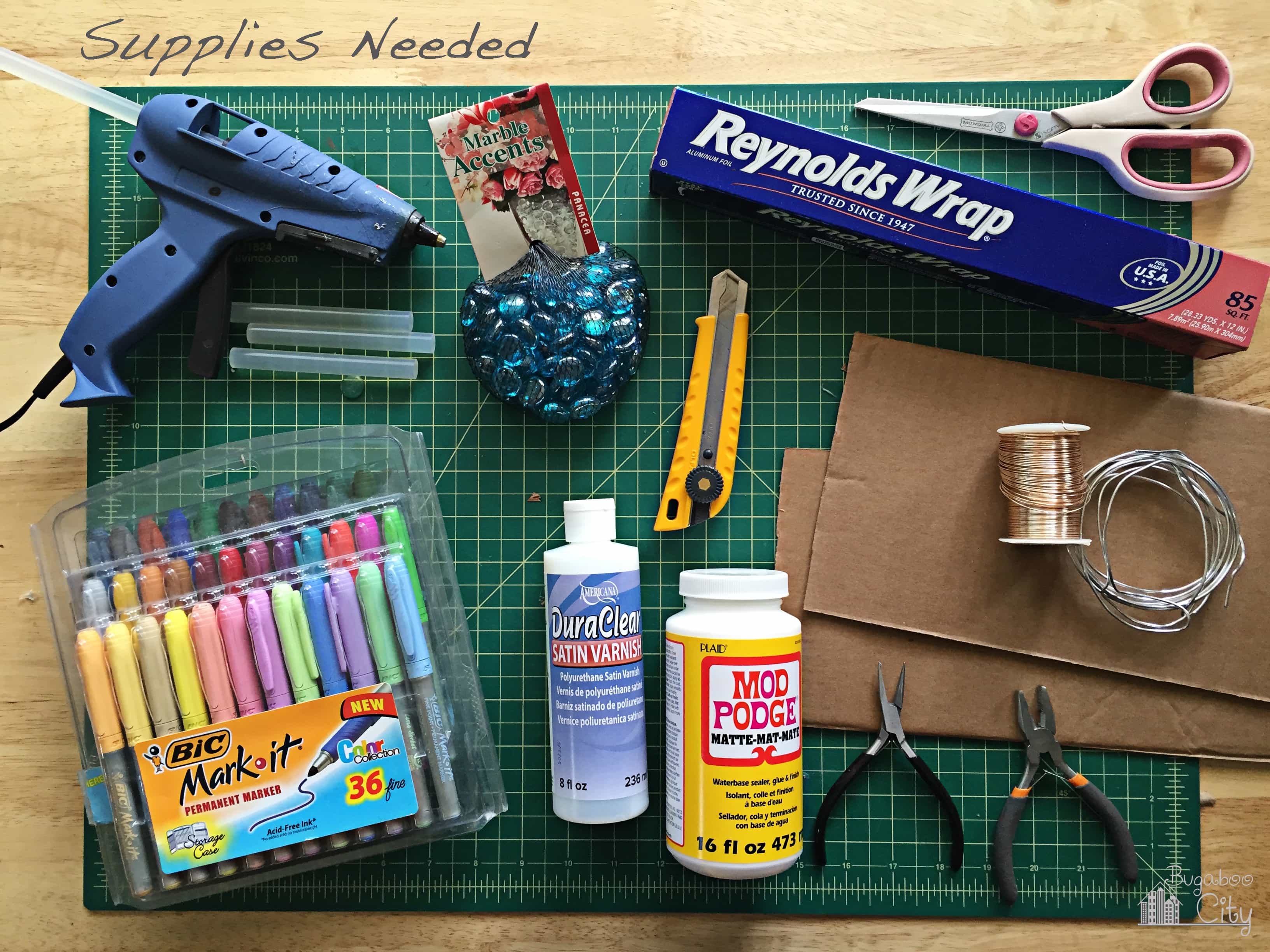 Supplies needed for butterfly garden ornaments including hot glue, cardboard and tin-foil.