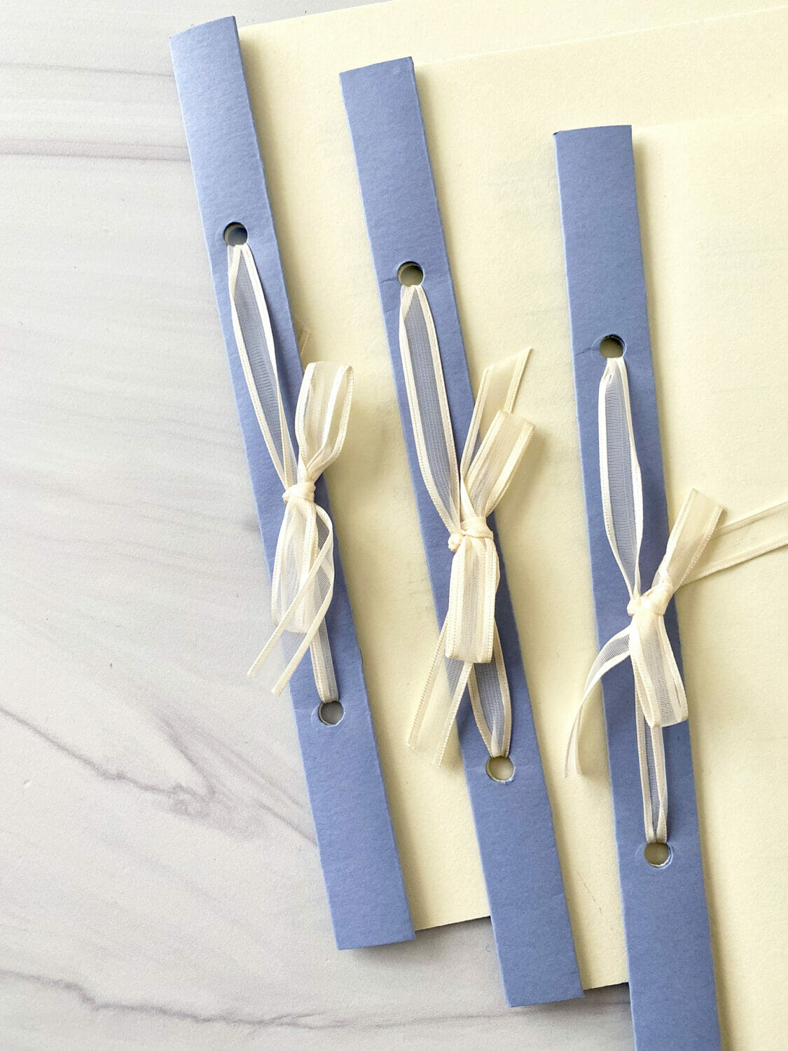 Three ceremony programs lined up showing the ivory ribbon bows tied in the bindings.