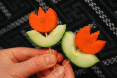 Carrots and cucumbers are used to create a cute flower with a toothpick.