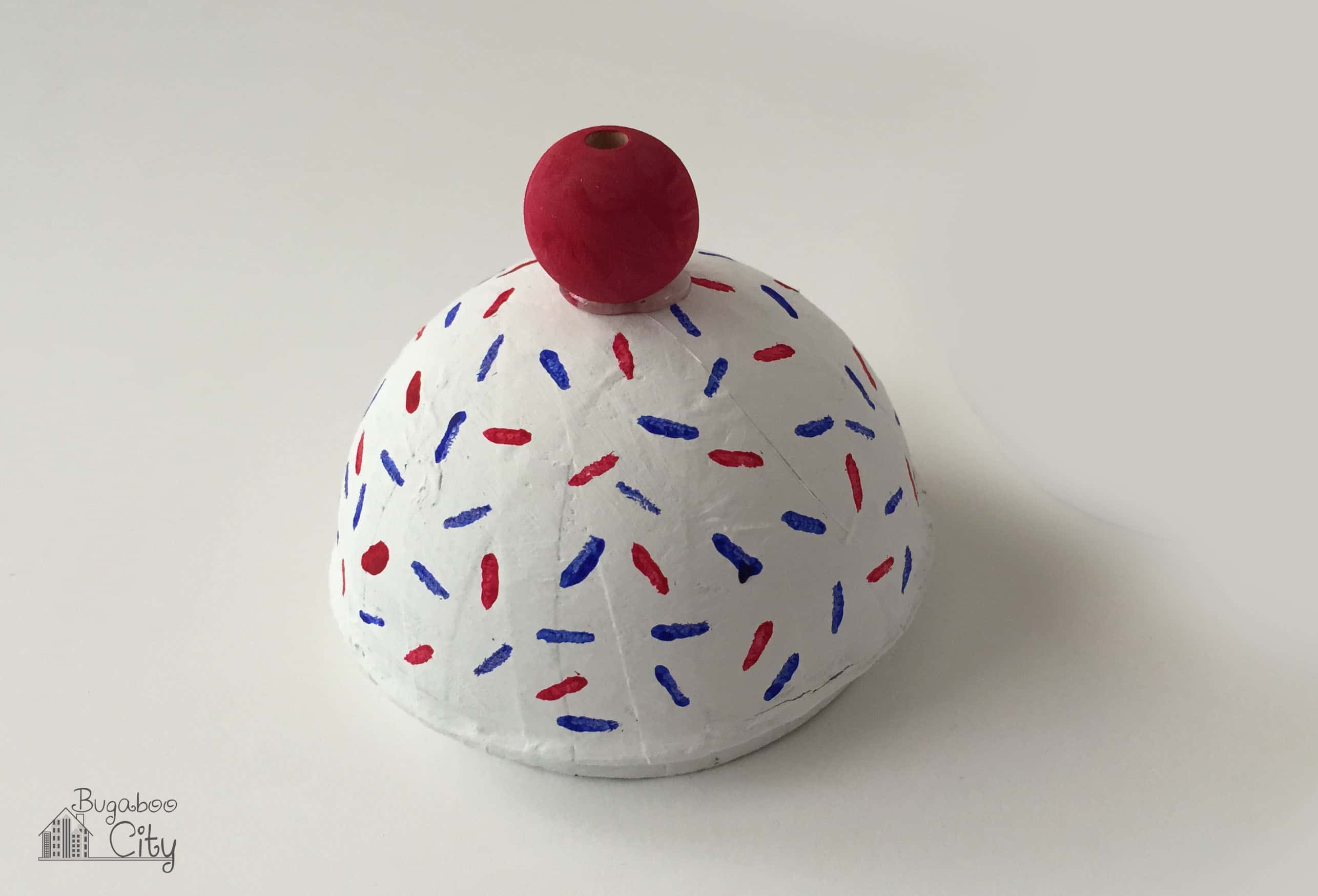 Ice cream cone lid with a wooden bead painted red.