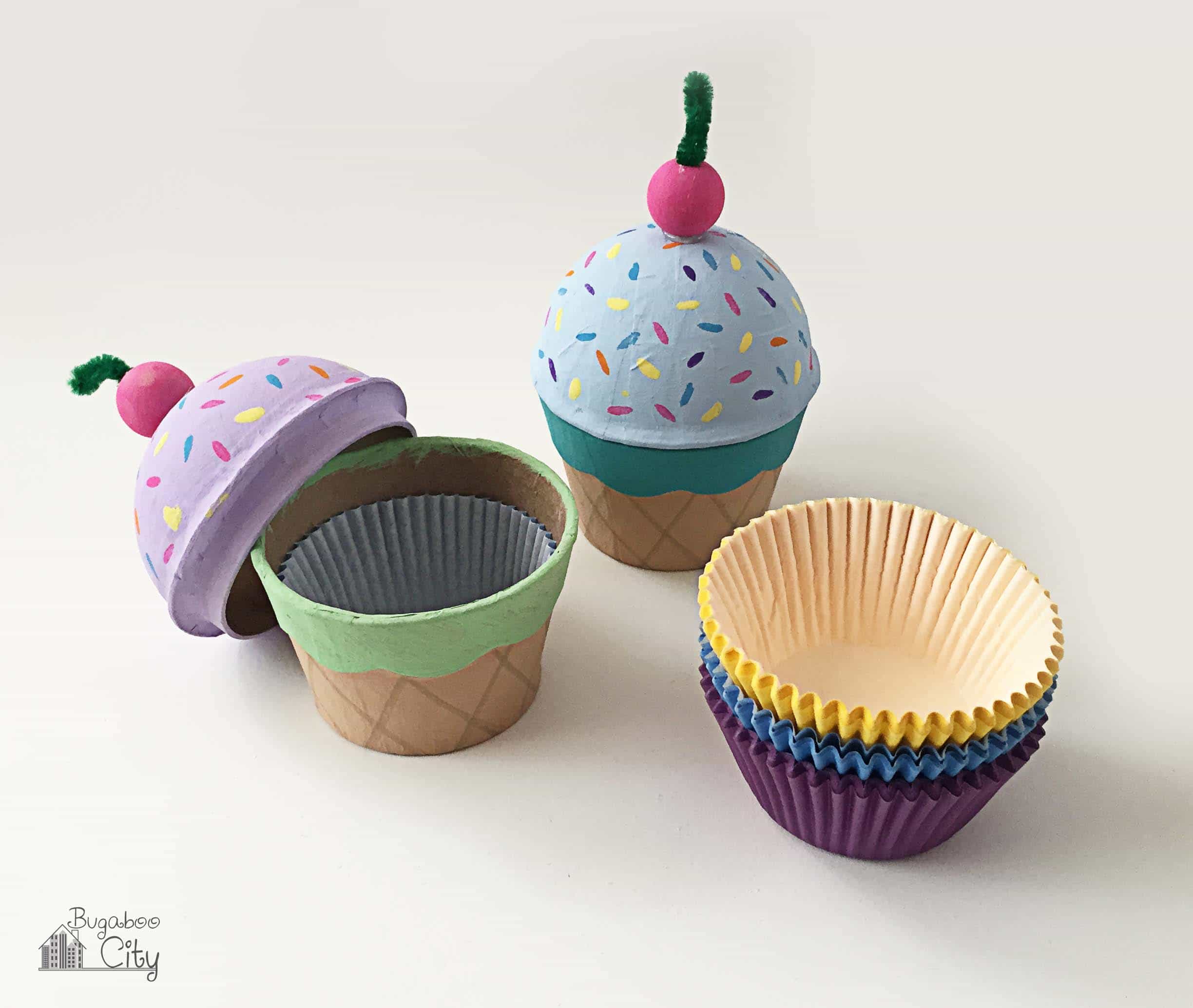 A stack of cupcake liners sit next to two cardboard ice cream cone boxes.