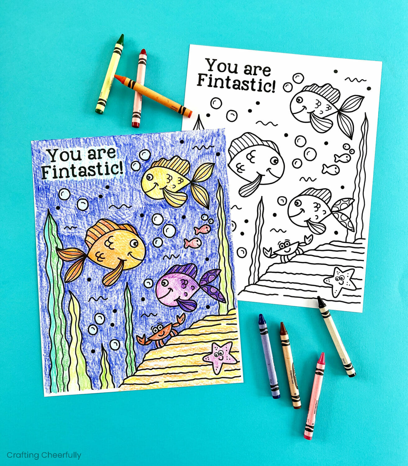 Two fish coloring pages lay on a turquoise surface.