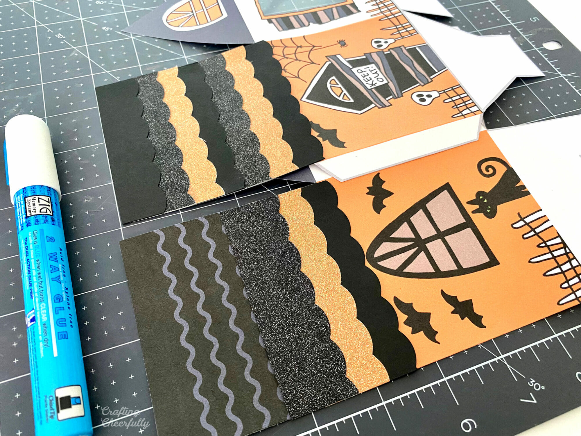 Printable boxes laying on a black cutting mat with roof pieces being added.