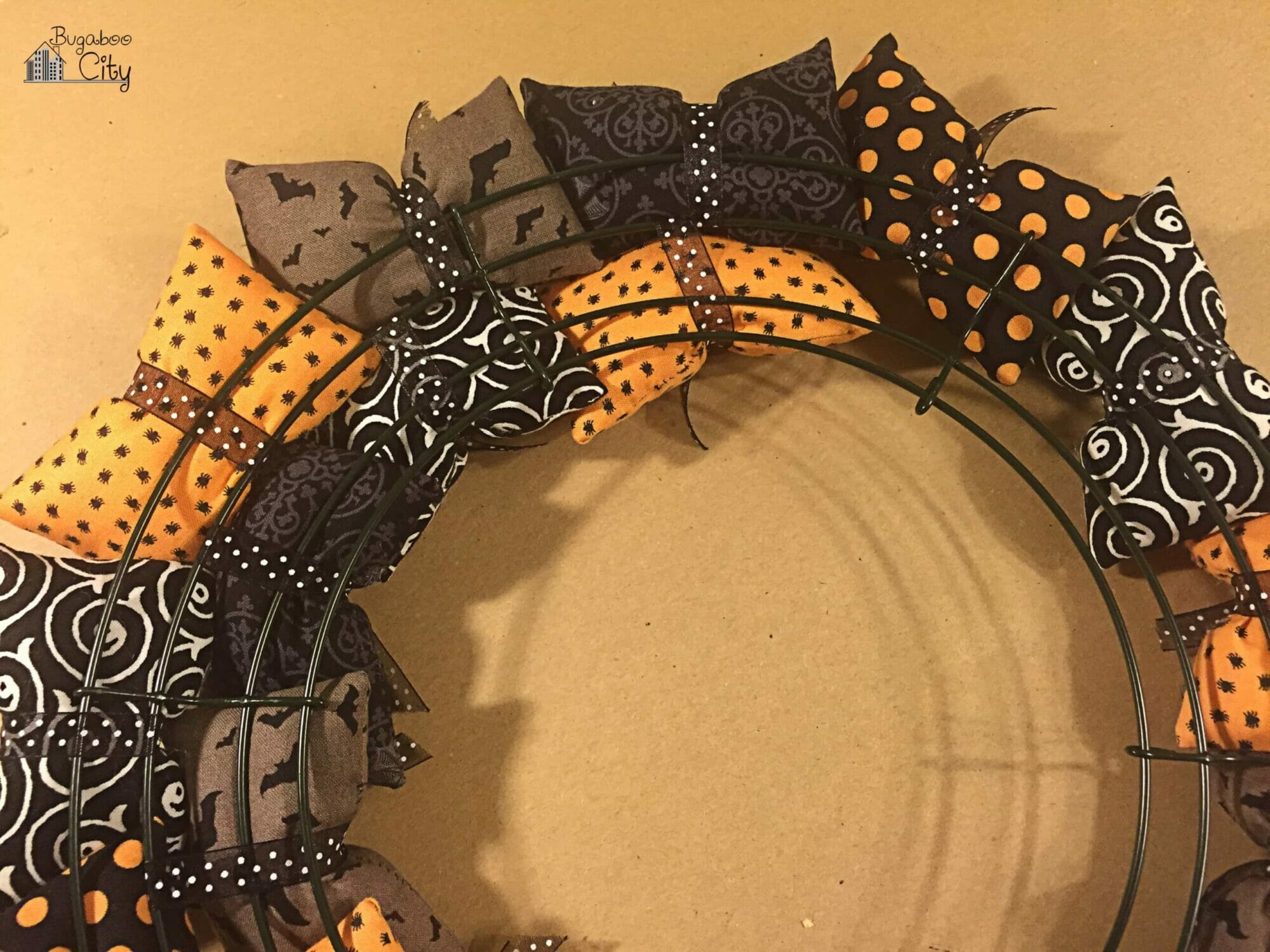 The back of the partially assembled wreath shows the ribbon going around two rungs of the wire wreath form.