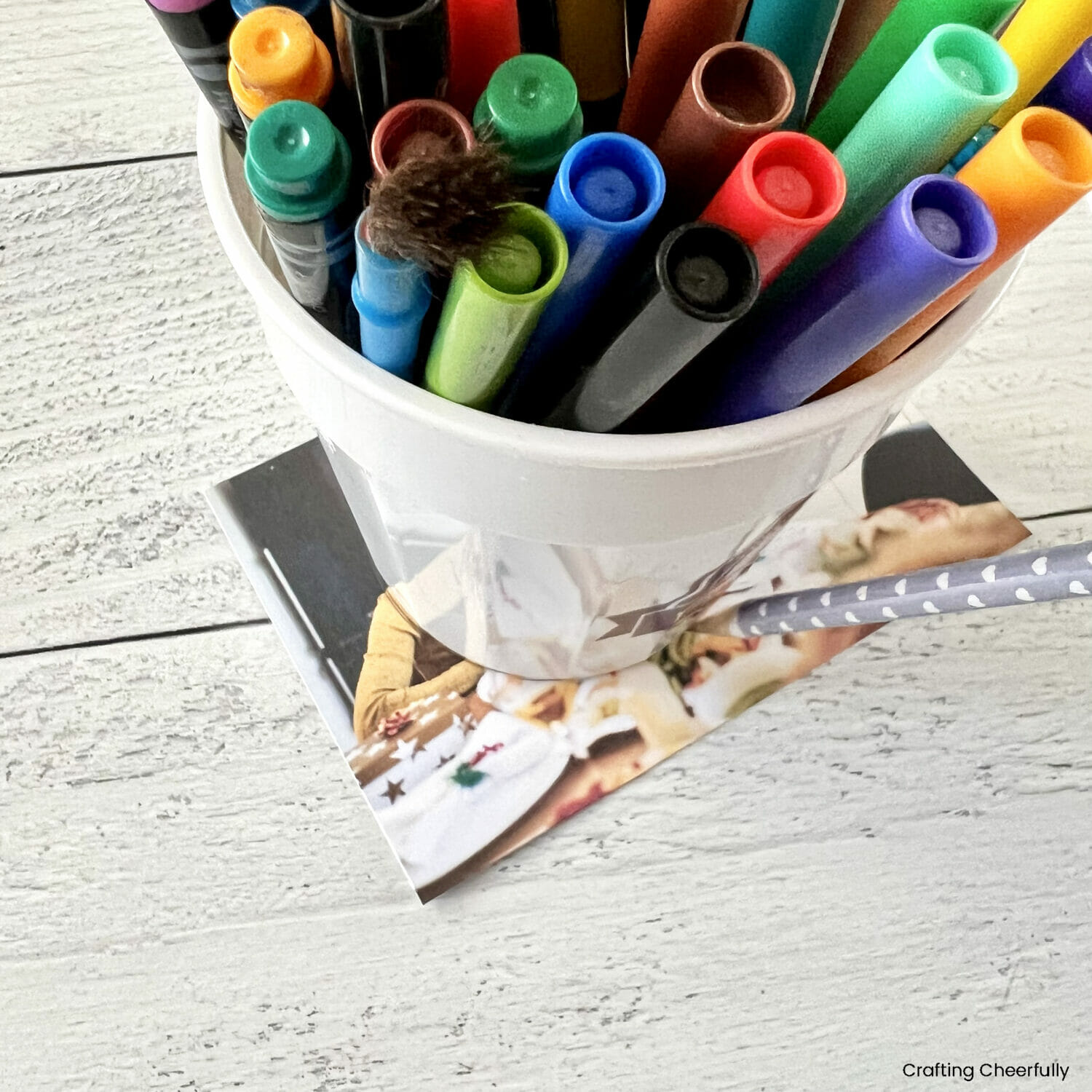 A cup of markers sits on top of the photo and is traced.