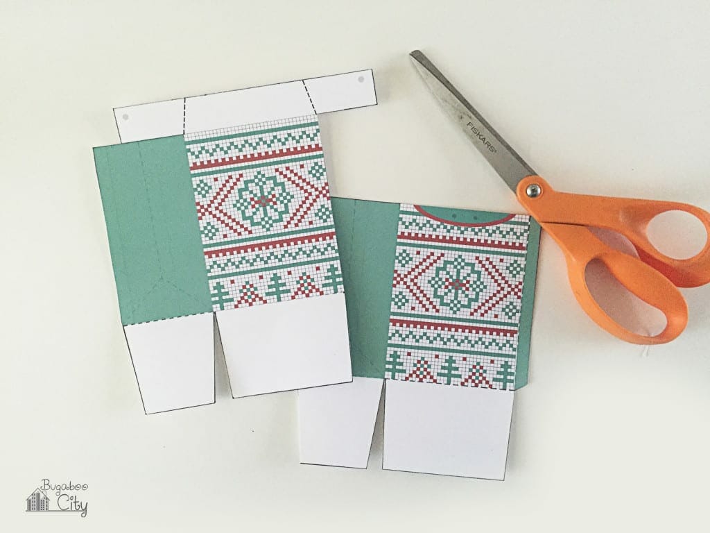 Two pieces of sweater treat box are cut out and lay next to a scissors.