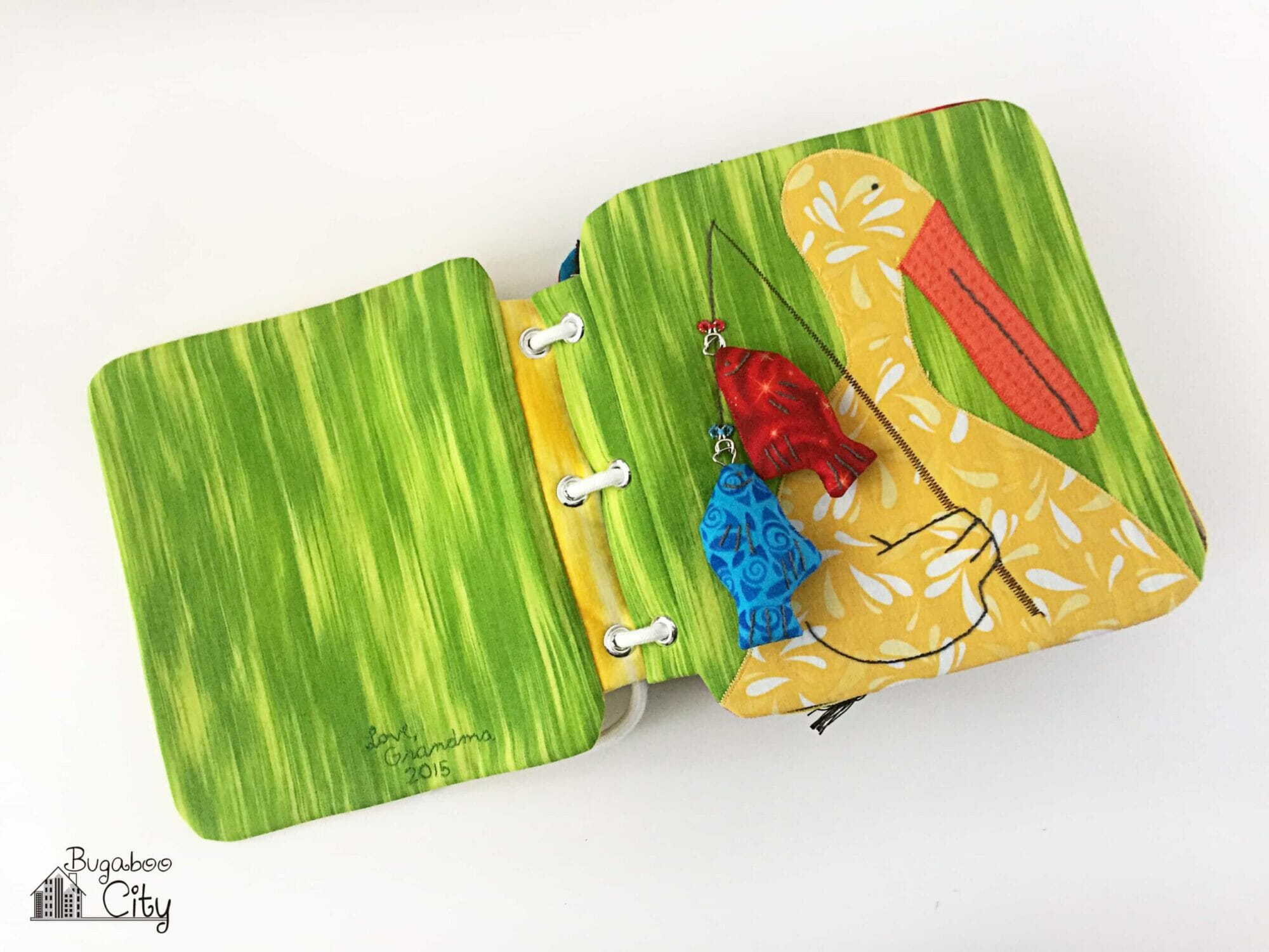 Fabric book page with an appliqué pelican and fabric fish.