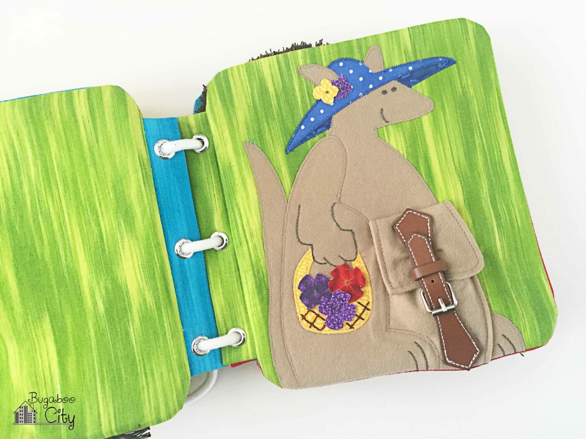 Fabric book page with felt kangaroo and a pouch closed with a buckle.