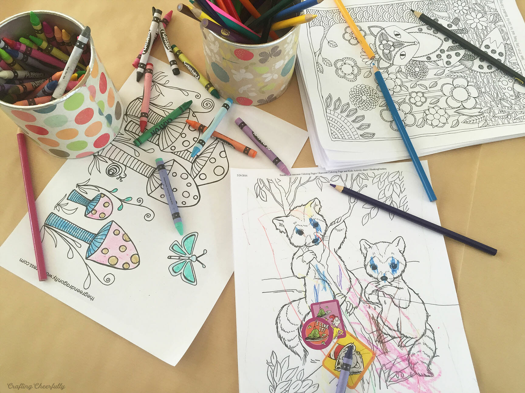 Coloring pages colored by children lay next to canisters of crayons.