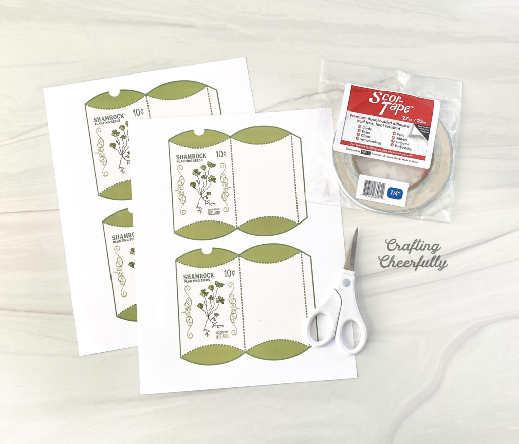 Printable Shamrock Treat Box files lay on a table with a scissors and double-sided tape.