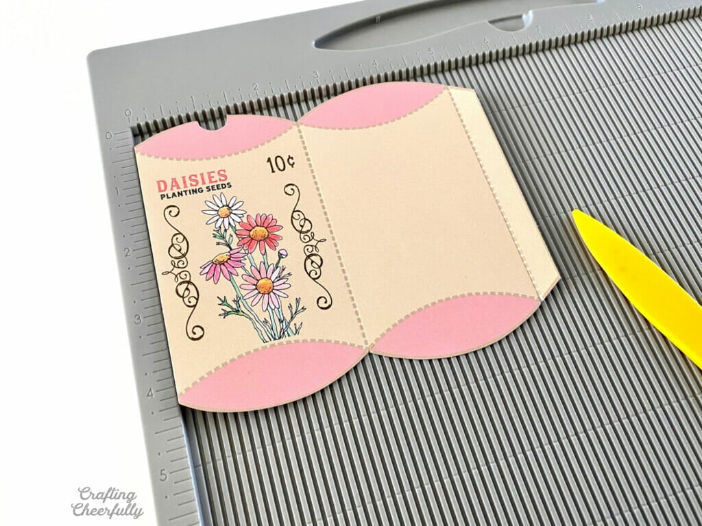 Scoring board with a flower seed treat box laying on it with a yellow stylus.