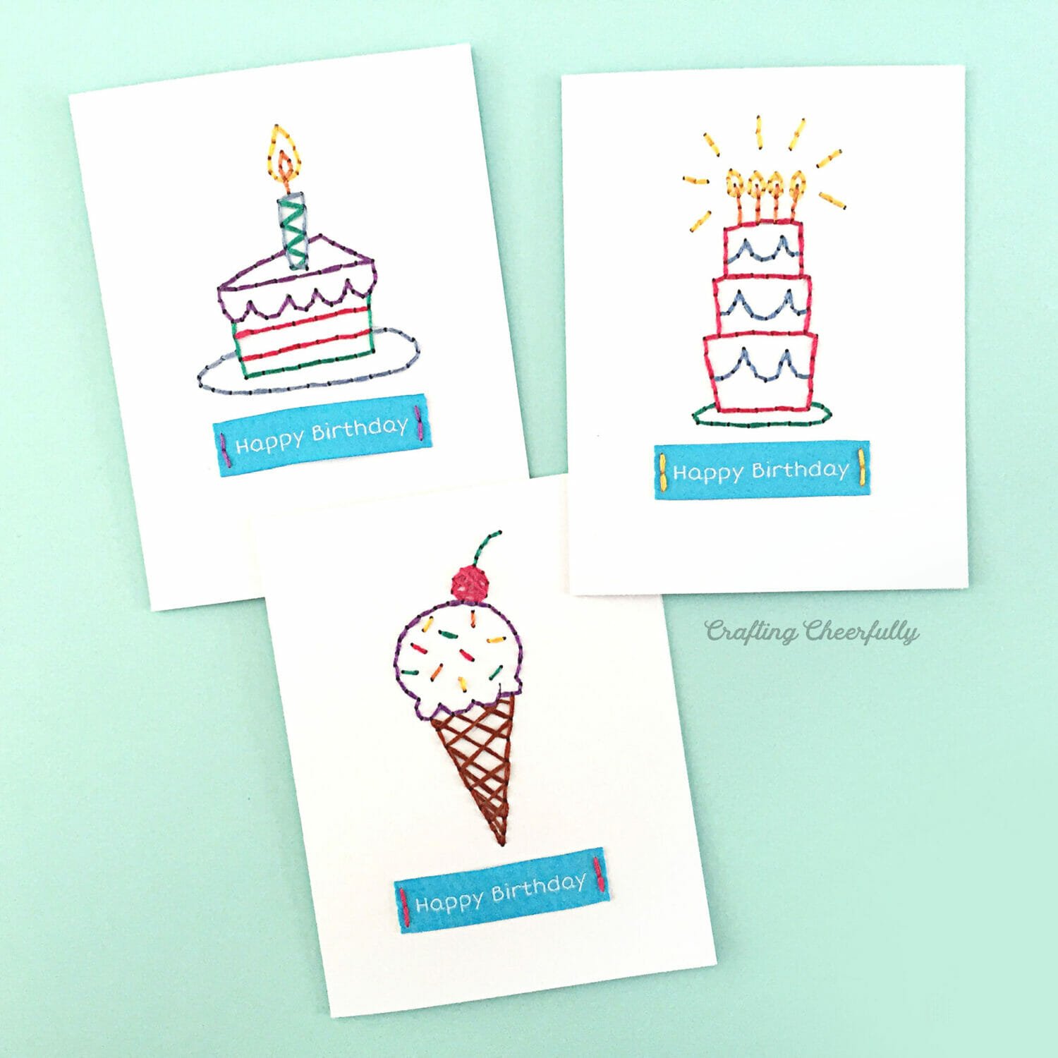 Three birthday cards with embroidered designs on them.