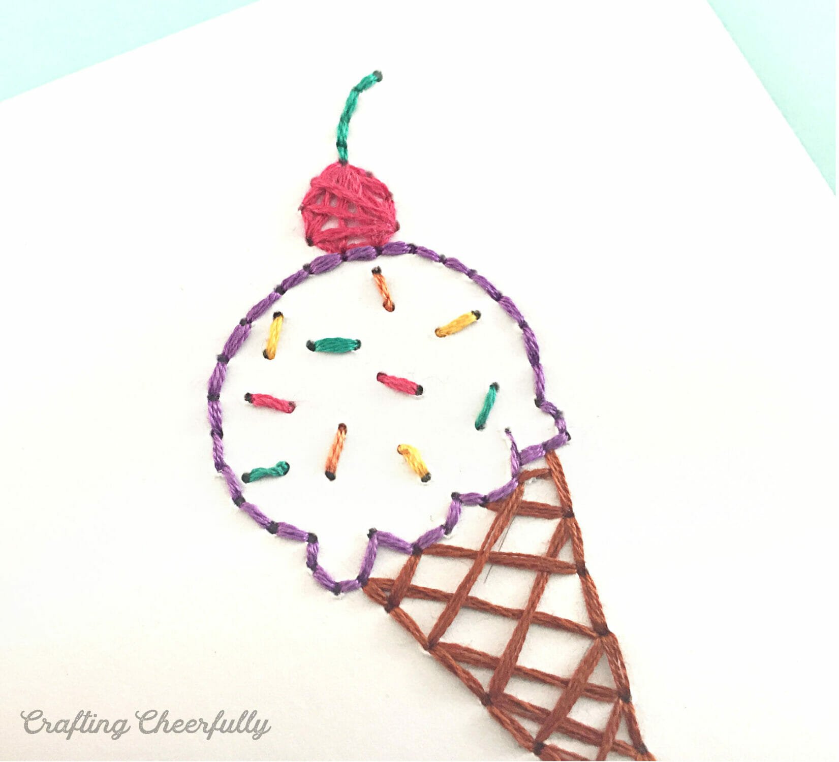 An ice cream cone is stitched to the front of a white paper card.