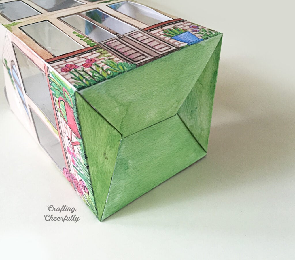 Printed paper greenhouse lays on a white surface.