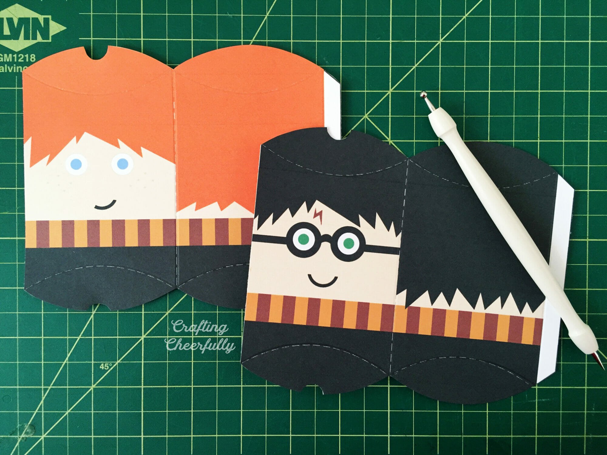 Ron and Harry Potter paper treat boxes lay on a green mat with a stylus.