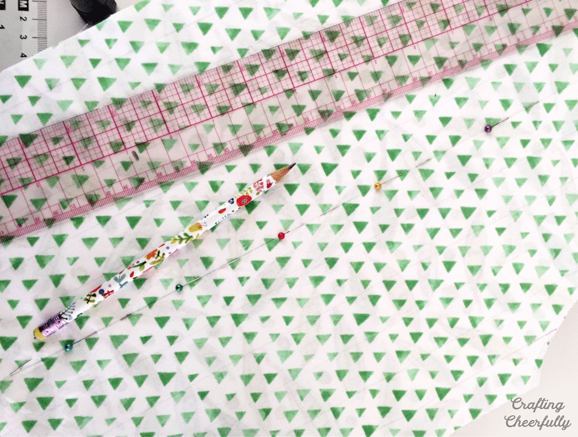 A ruler is used to mark the center of the apron with pencil; pins are placed along the pencil line.