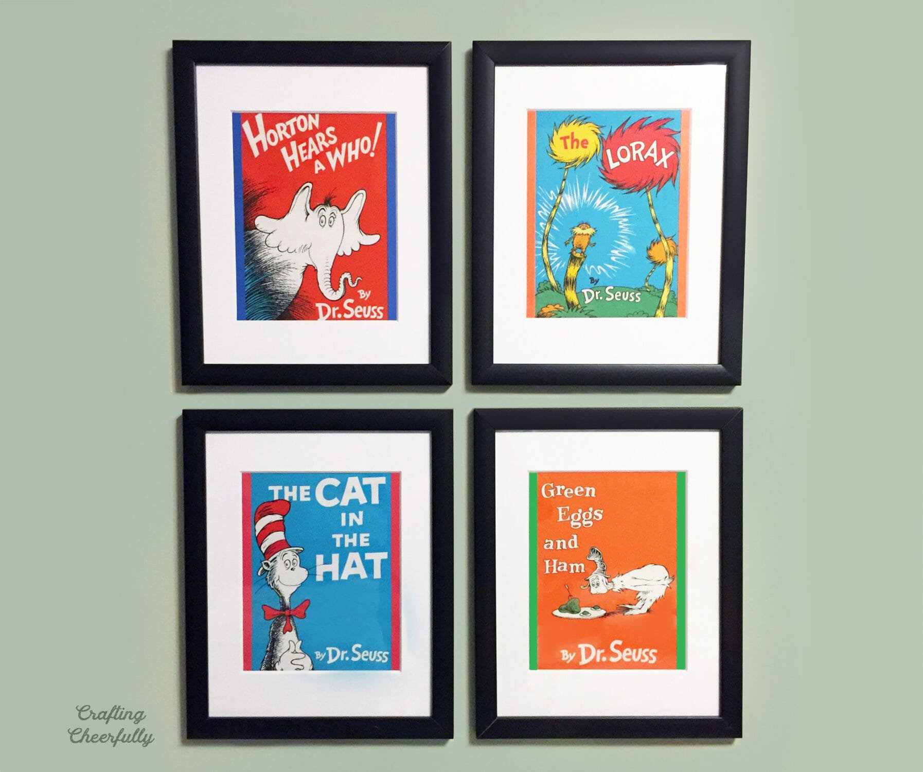 Four black frames with Dr. Seuss fabric panel book prints in them.