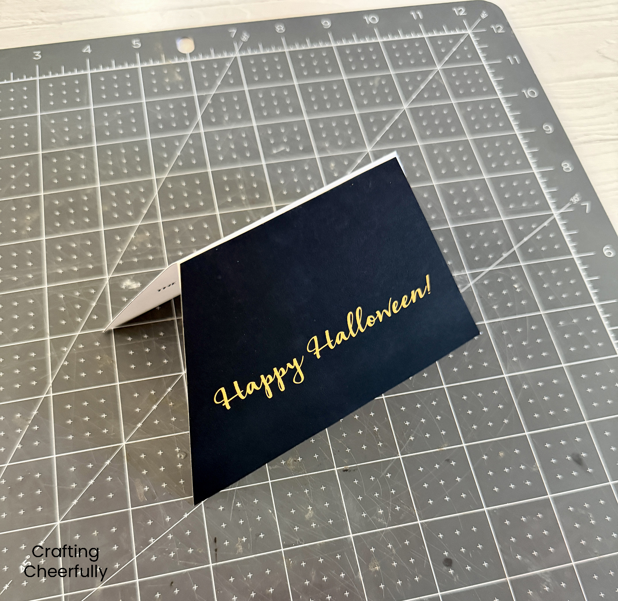 The bottom of the snow globe card is folded in half and resting on a self-healing mat.