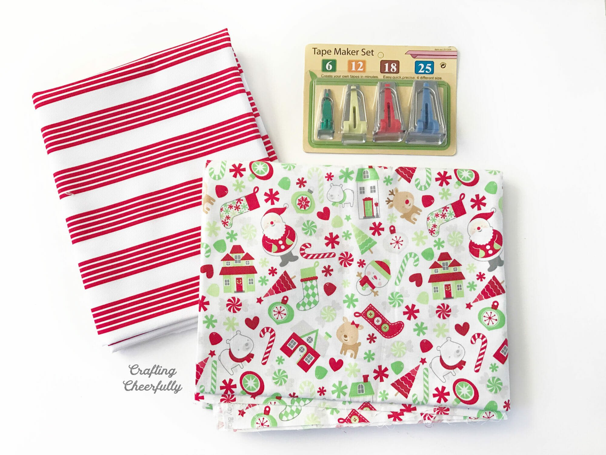 Two holiday-themed fabrics folded lay next to a package of bias tape makers.
