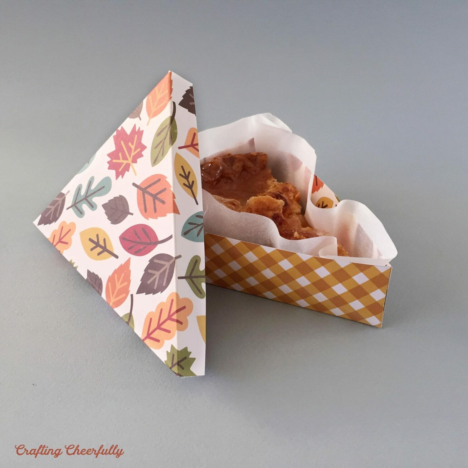 Pie slice box for Thanksgiving lays on a gray surface.