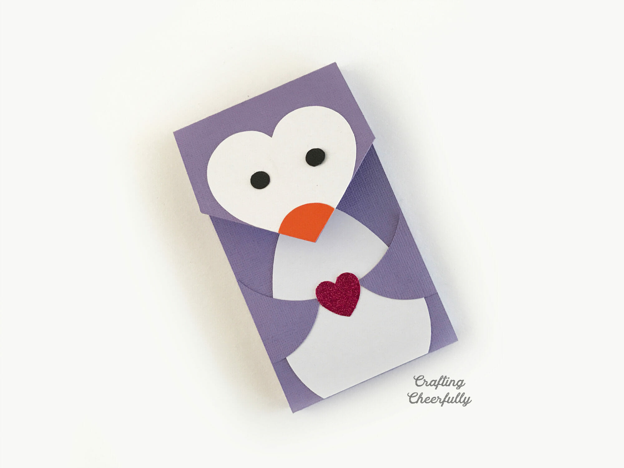 Purple penguin notepad with heart-shaped face is holding a pink heart.