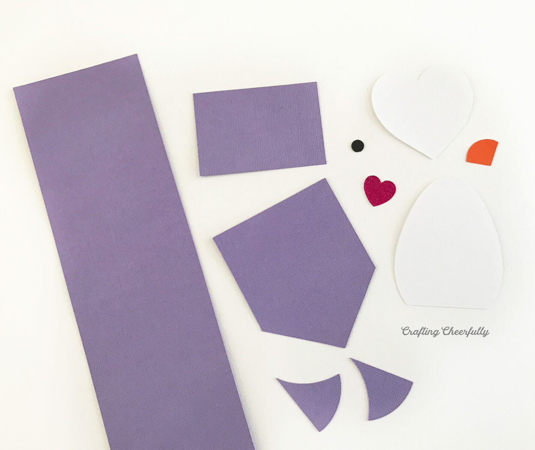 Paper pieces to create a penguin notepad are cut out and laying on a table.