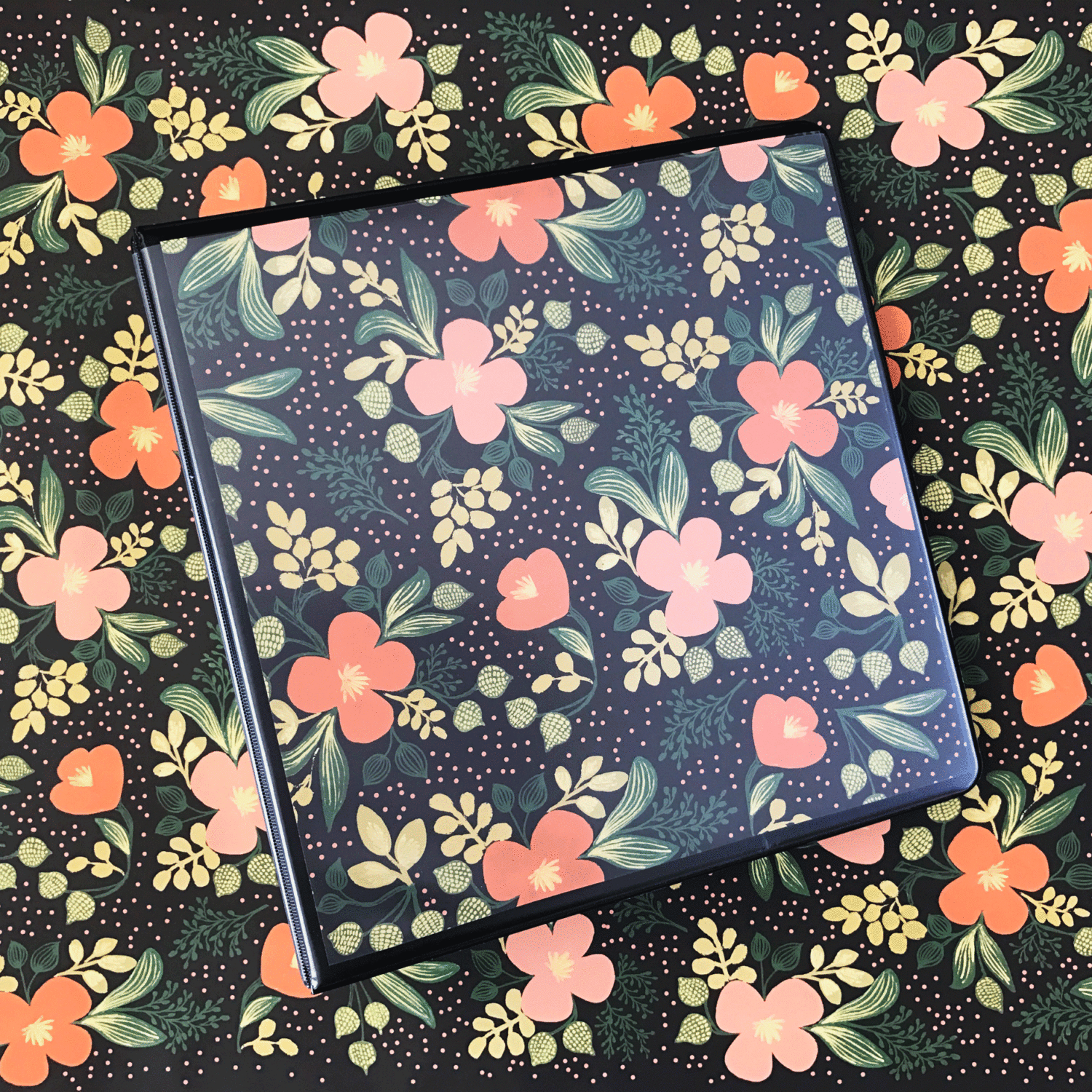 3 ring binder filled with floral paper sits on a table covered with the same paper.