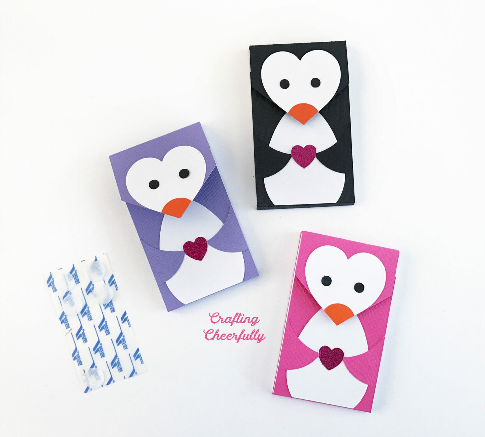 Three paper penguin notepads lay next to a sheet of Velcro fasteners.