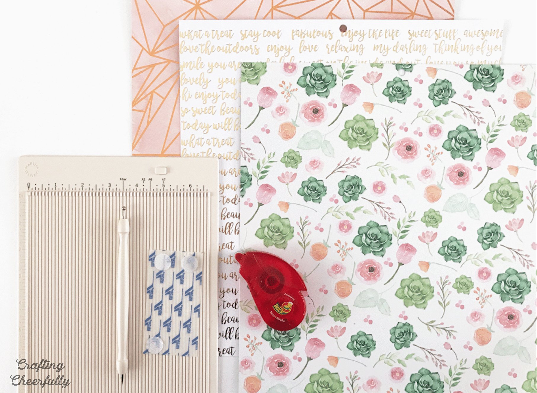 Decorative scrapbook paper, scoring board and tape runner. 