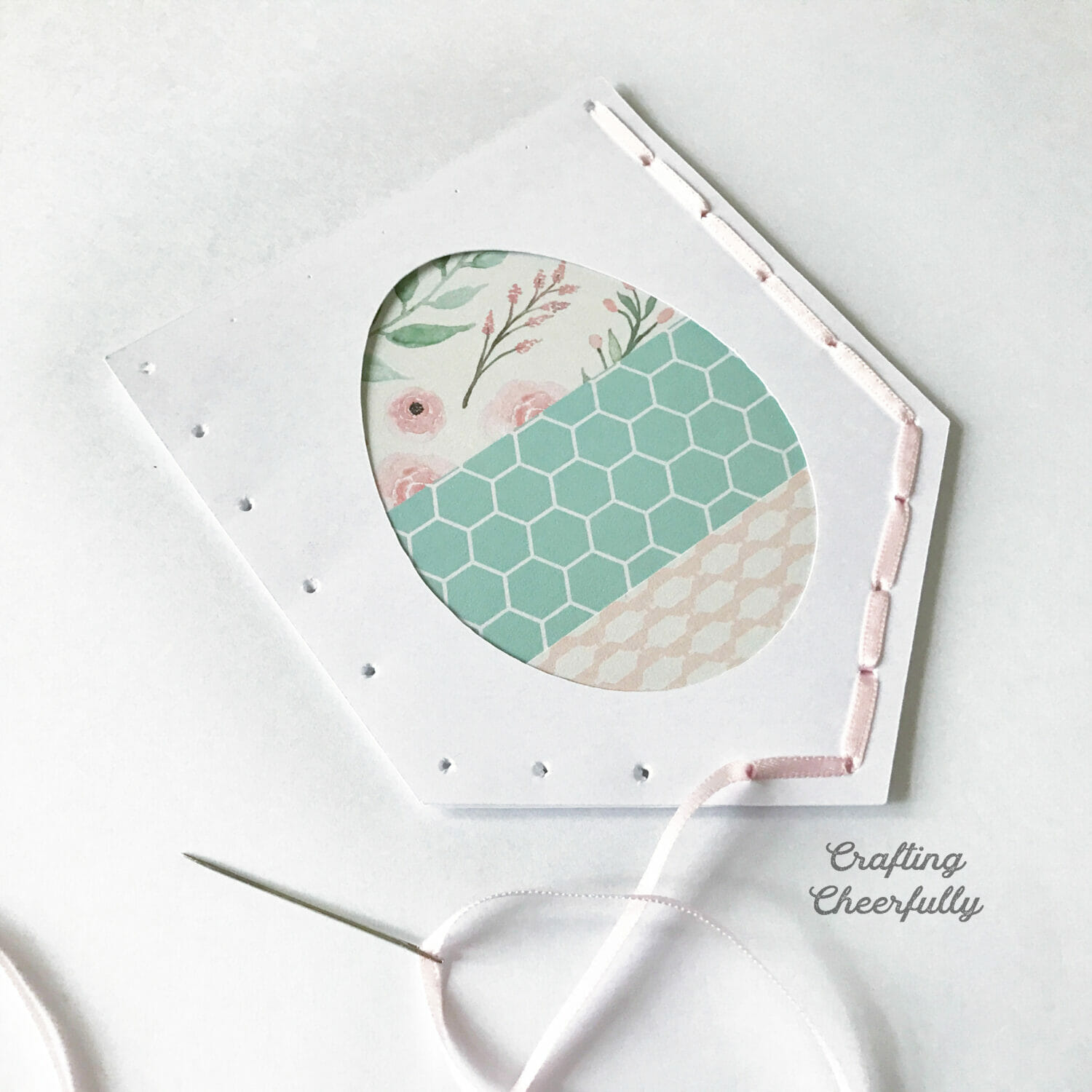 The pennant is stitched on two of the five sides with thin pink ribbon.
