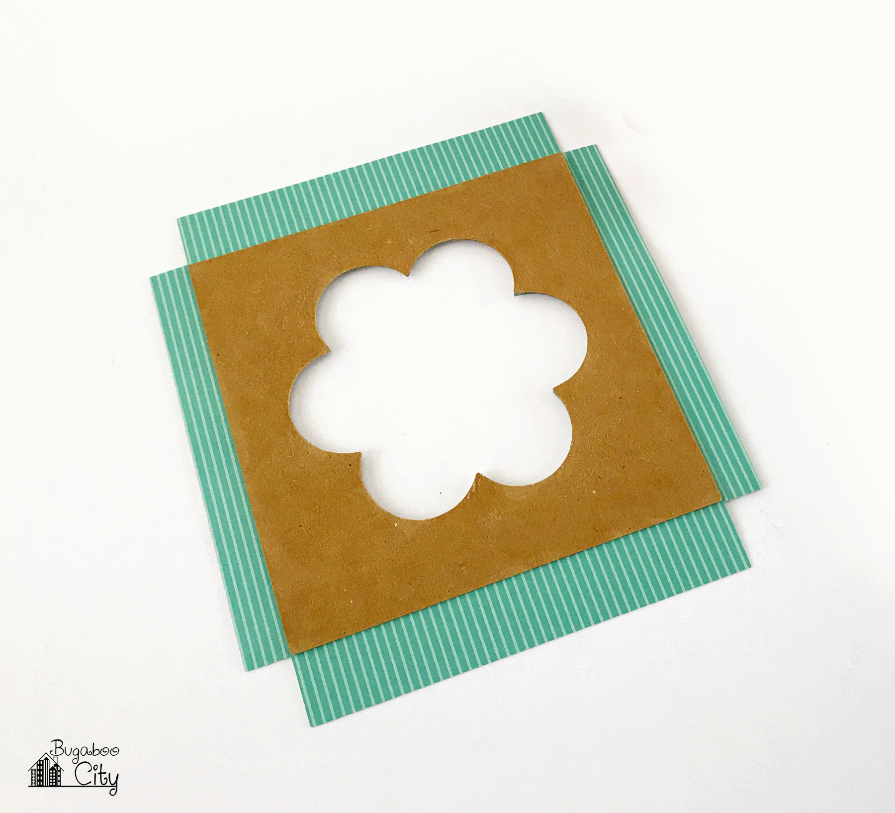 Chipboard with flower cut out lays on top of matching paper.