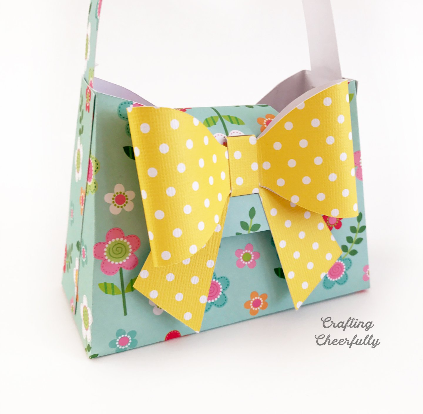 Paper purse made from teal floral paper and a giant yellow polka dot paper bow.