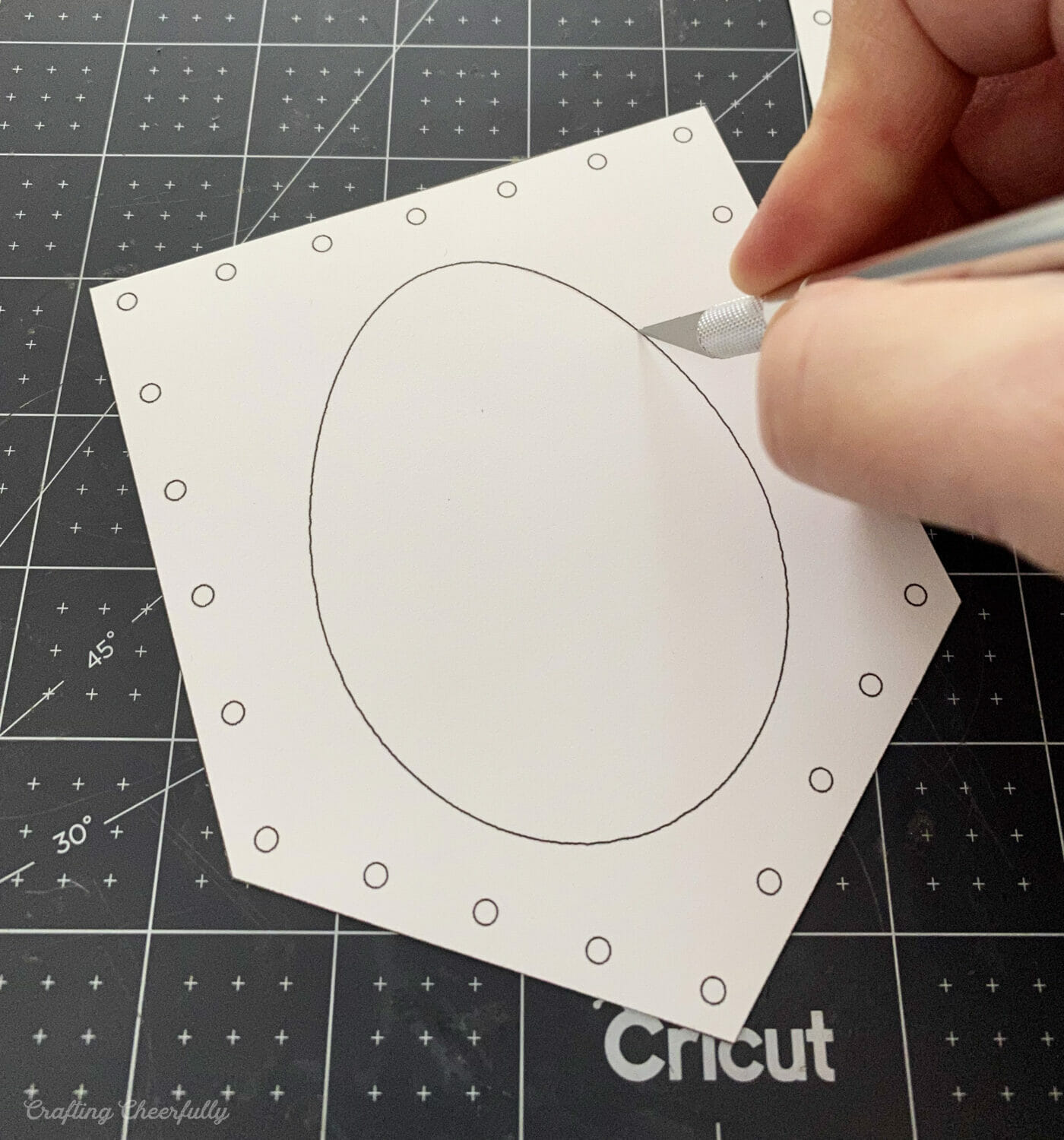 An egg is cut from the center of a pennant using a craft knife.