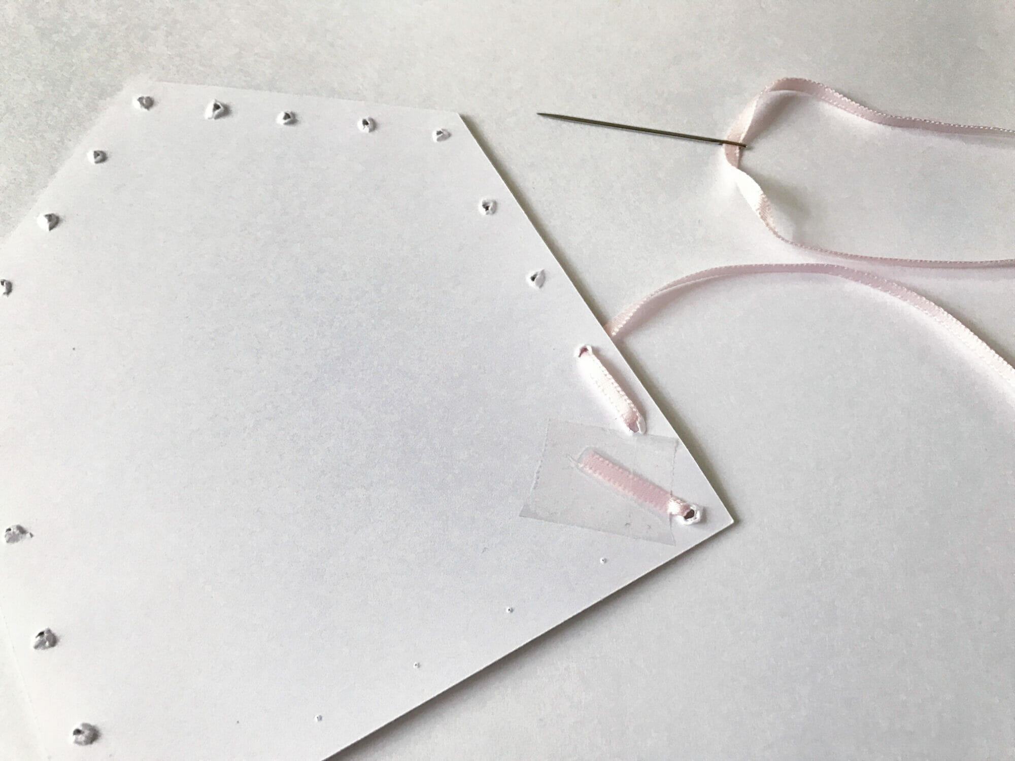 The back of a pennant showing the start of a backstitch using ribbon around the edges of the pennant.