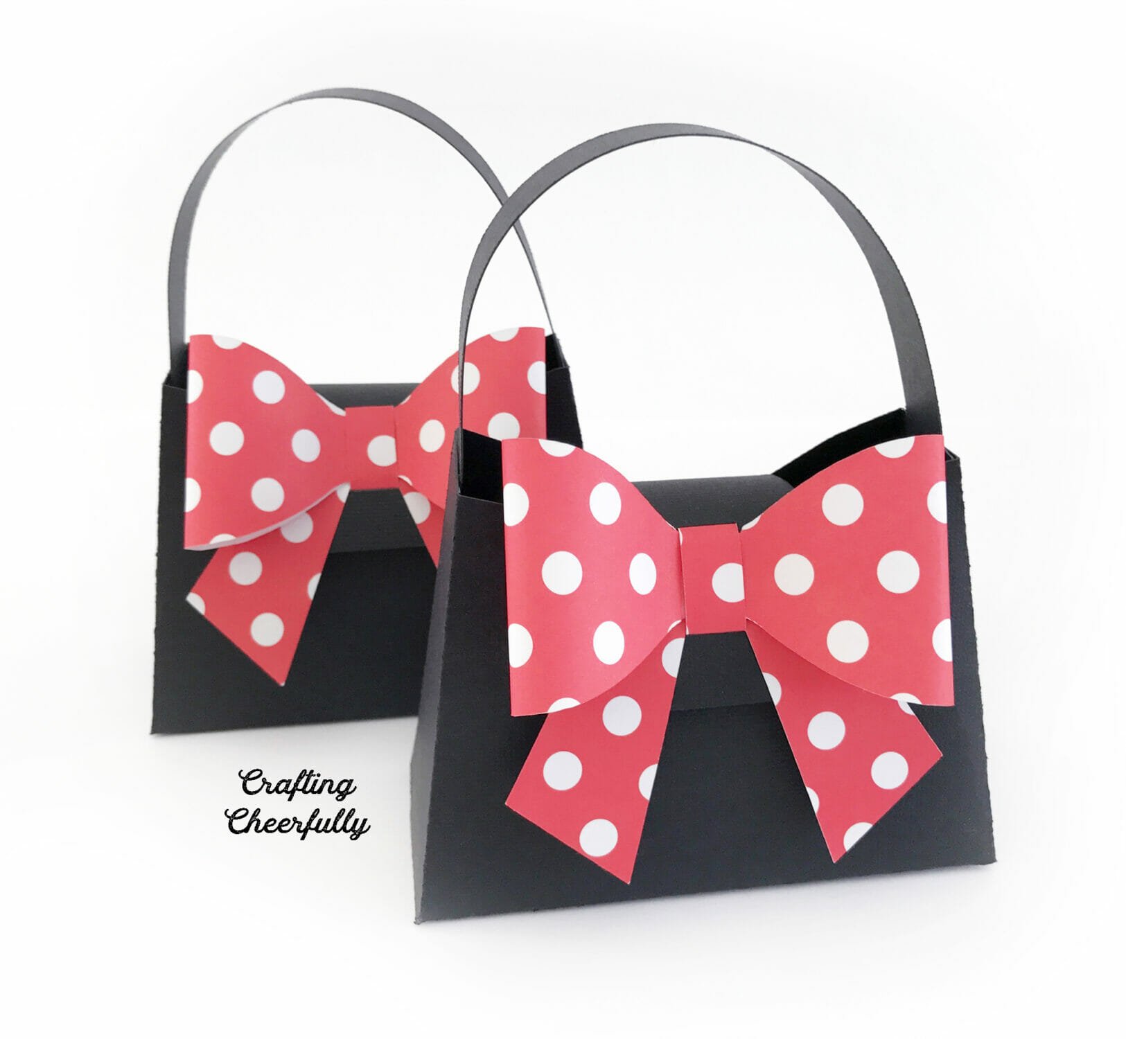 Two black paper purses with red and white polka dot bows on them.