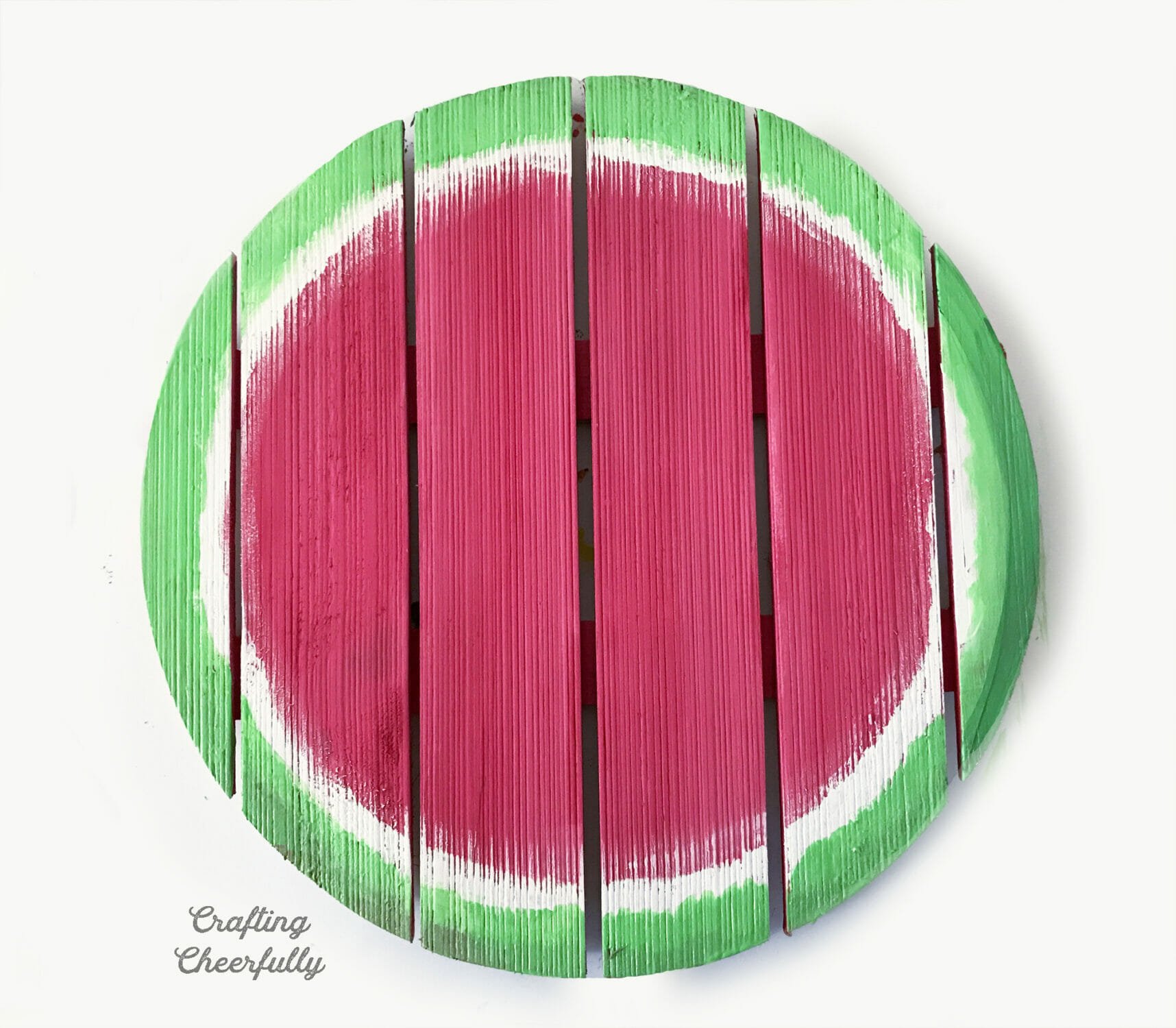 A round wood sign painted pink with a white and green border around it.