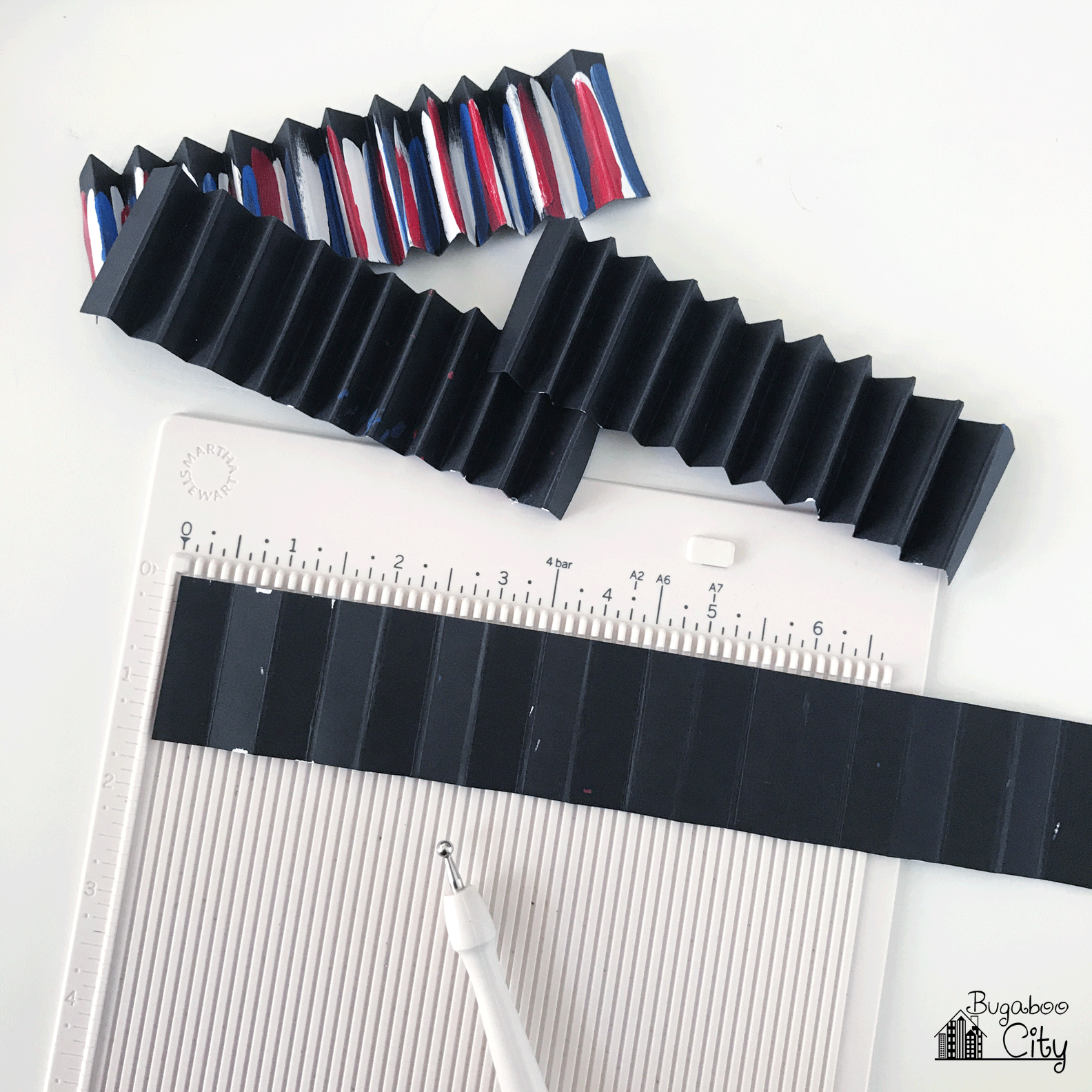 Strips of black paper painted are scored every 1/2" with a scoring board and stylus.