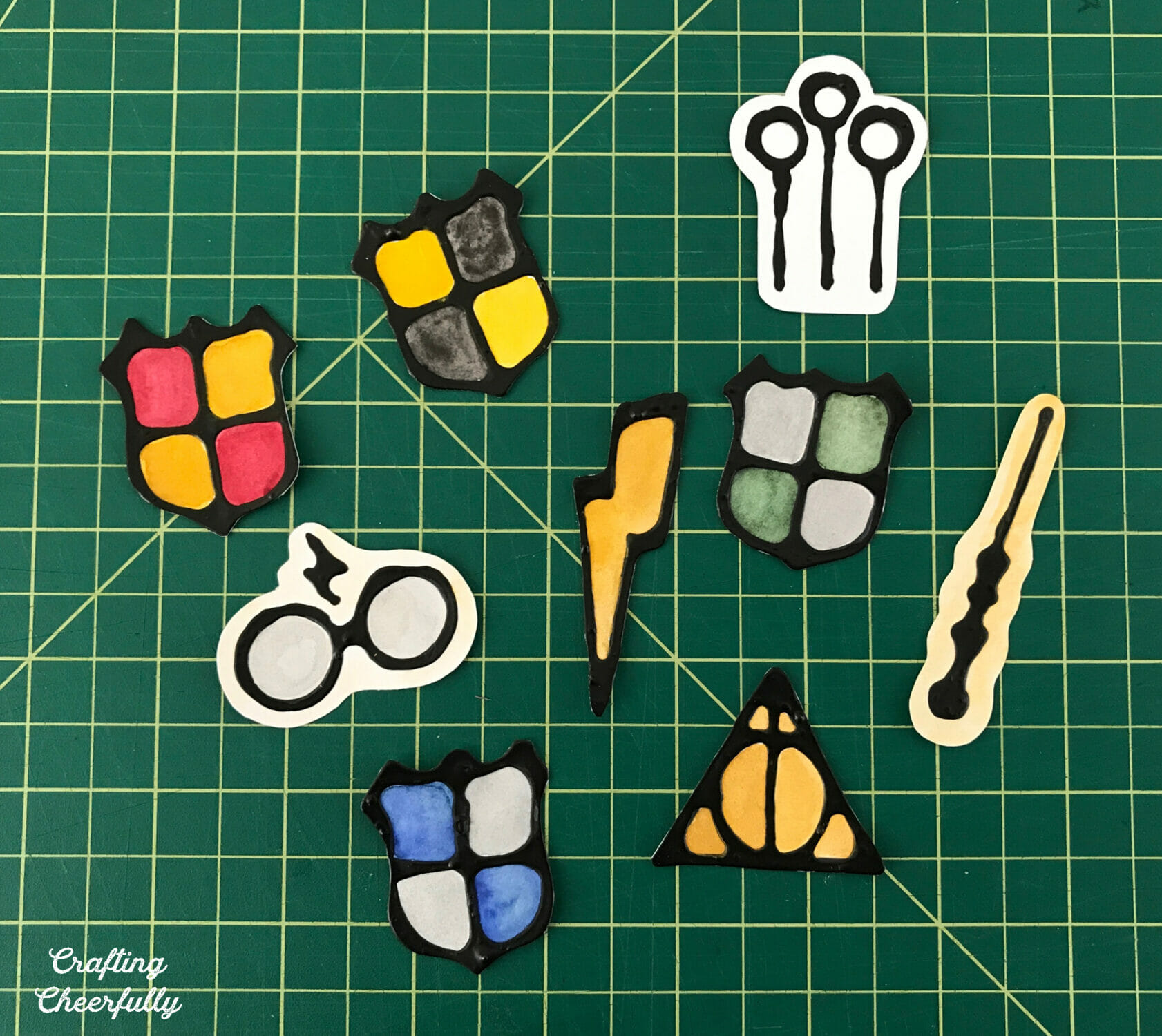 Harry Potter magnets are cut out and lay on a green cutting mat.