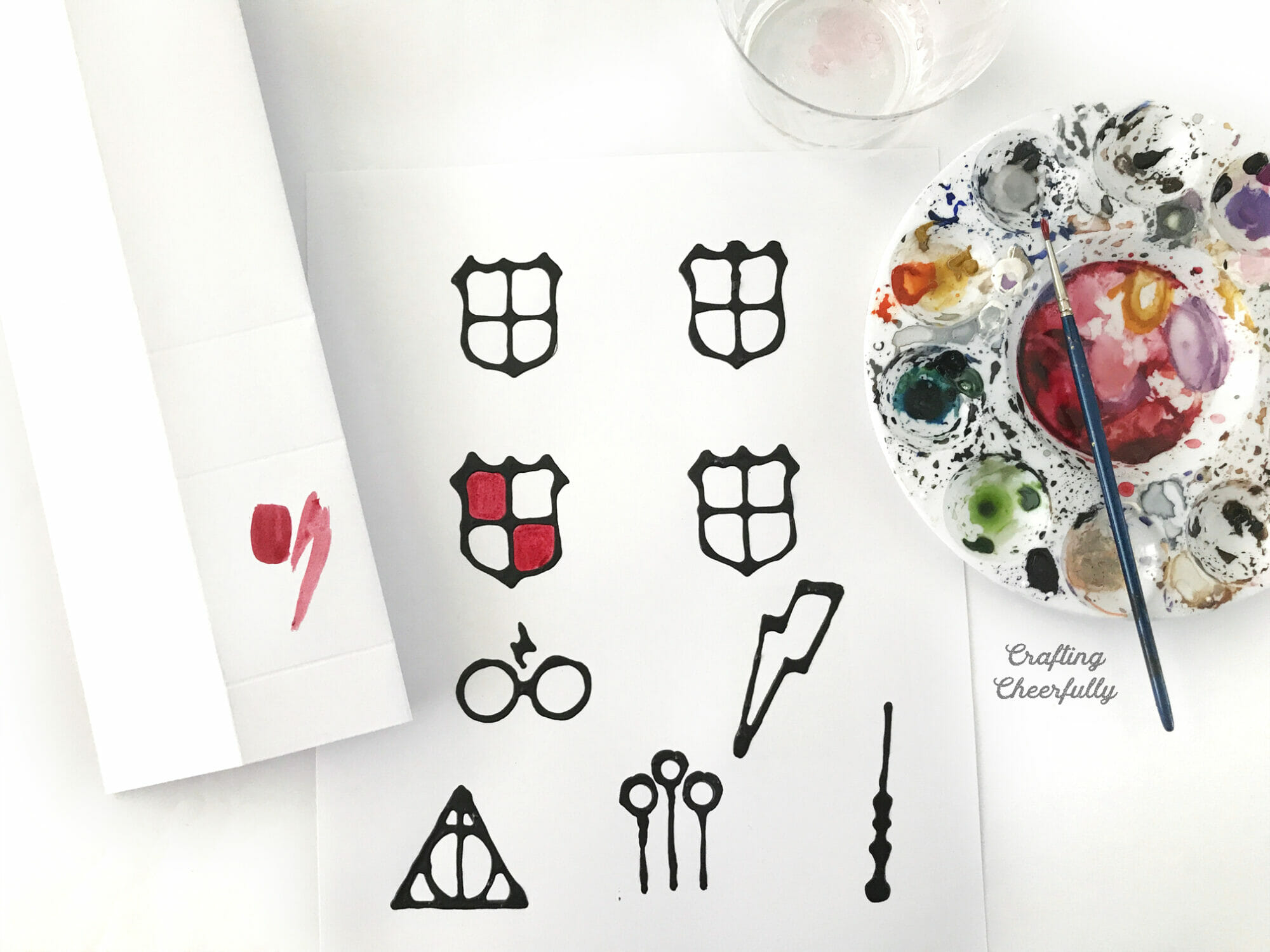 A colorful palette of watercolor paint lays next to the template with black glue outlining them.