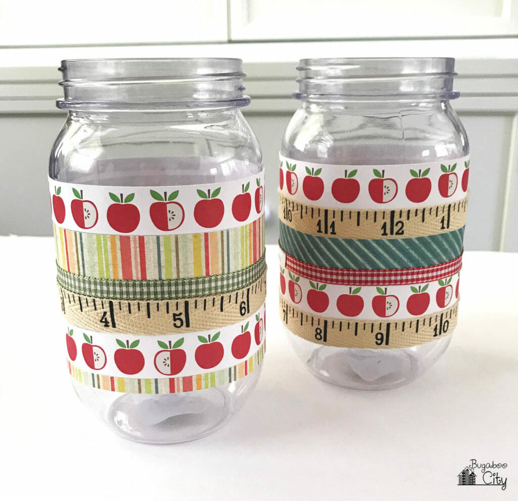 Two mason jars with ribbon and paper wrapped around the jars.