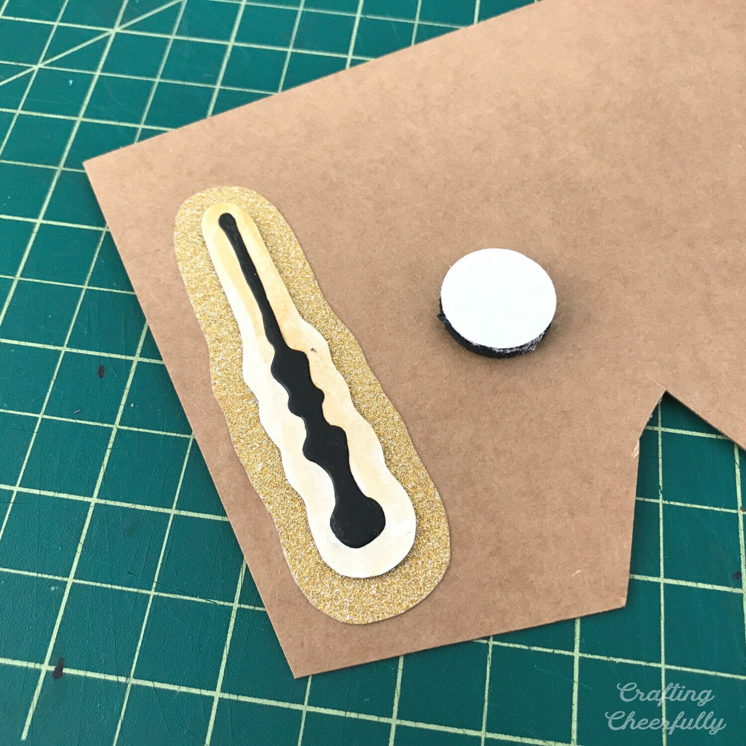 Wand magnet is surrounded by gold glitter paper and glued to chipboard.